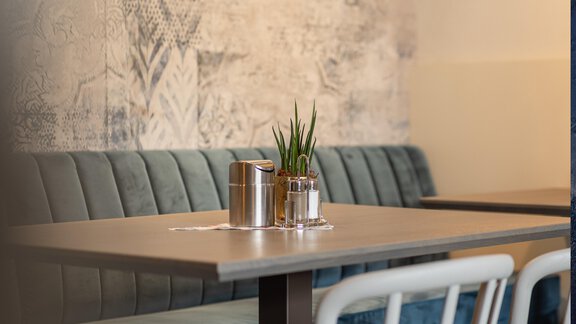 A cozy table in a modern restaurant with an elegant bench. On the table, there is a small plant and drinks. - Haus Verwall Appartements - Obergurgl 