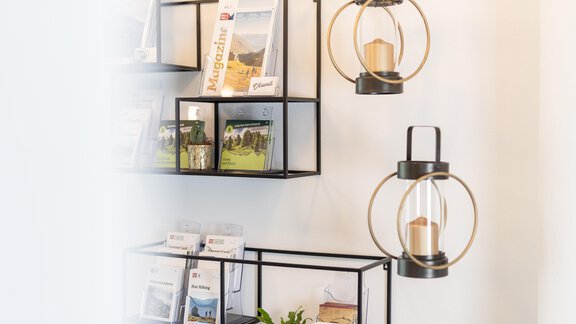 A modern room with black shelves displaying brochures and magazines. Two stylish lamps hang decoratively on the wall. - Haus Verwall Appartements - Obergurgl 