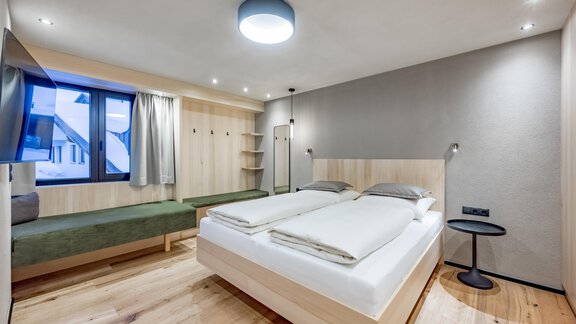 A modern bedroom with a double bed and a cozy seating area. Large windows provide plenty of daylight and a pleasant atmosphere. - Hotel-Garni Pirchhütt - Obergurgl 