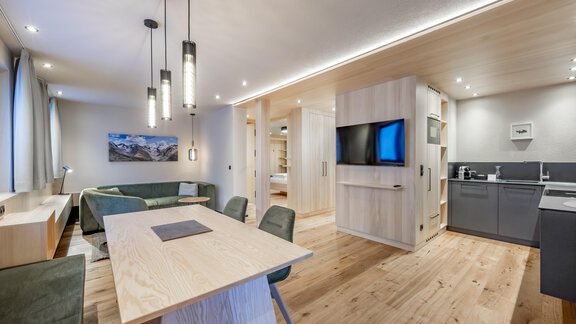 A modern living room with a large dining table and sofas. The elegant kitchen is well-equipped and there is plenty of daylight. - Hotel-Garni Pirchhütt - Obergurgl 