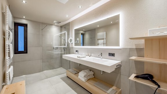 A modern bathroom with a large mirror and a clean, minimalist design. The walls are in neutral tones and the lighting creates a bright atmosphere. - Hotel-Garni Pirchhütt - Obergurgl 