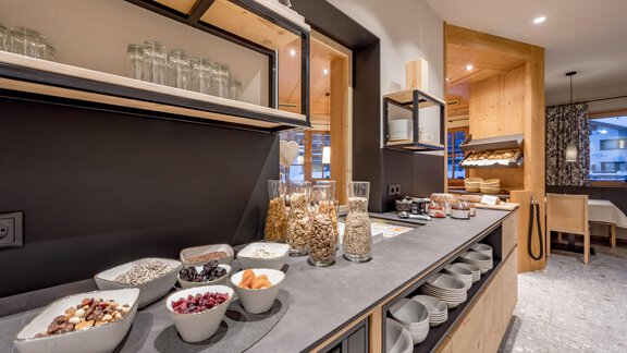 A modern kitchen with a selection of breakfast ingredients on a table. Glasses, bowls, and dishes with muesli and nuts are neatly arranged. - Hotel-Garni Pirchhütt - Obergurgl 