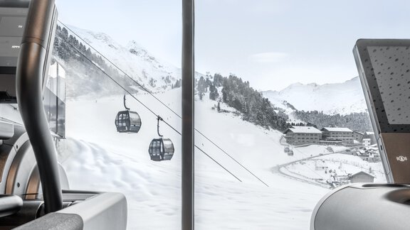 A view of snow-covered mountains with a cable car in the background. In the foreground, modern fitness equipment is visible. - Hotel Gotthard-Zeit - Obergurgl 