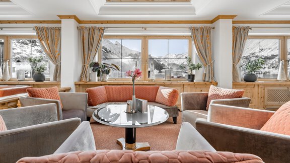 An elegant living area with cozy sofas and a central table. Large windows let in plenty of light and offer a view of the mountains. - Hotel Gotthard-Zeit - Obergurgl 