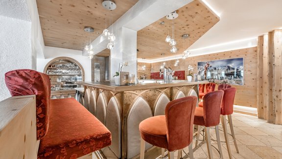 A stylish bar with elegant red chairs and a wooden ceiling. Chemical and cozy lighting creates an inviting atmosphere. - Hotel Gotthard-Zeit - Obergurgl 