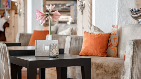 An elegant living area with comfortable sofas and colorful cushions. On a black table stands a vase with a beautiful flower. - Hotel Gotthard-Zeit - Obergurgl 