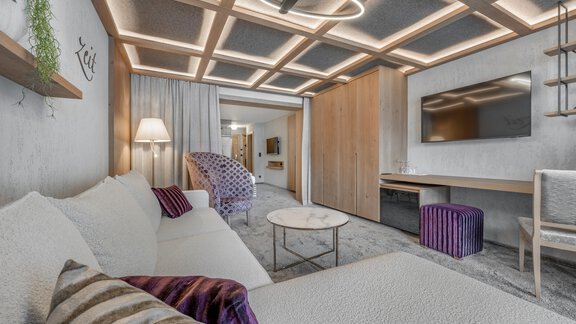 A modern living environment with a white sofa, a coffee table, and a large television. The renovation provides warm light and a cozy atmosphere. - Hotel Gotthard-Zeit - Obergurgl 
