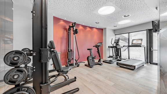 A modern gym with several training machines. The room is bright and well-equipped with wooden flooring. - Hotel Gotthard-Zeit - Obergurgl 