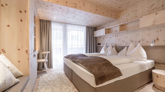 A cozy bedroom with wooden ceilings and walls. Two beds with white pillows and a soft carpet. - Hotel Olympia - Obergurgl 