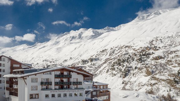 A beautiful hotel in the mountains, surrounded by snow. The majestic mountains and the clear sky create an impressive winter landscape. - Hotel Olympia - Obergurgl 