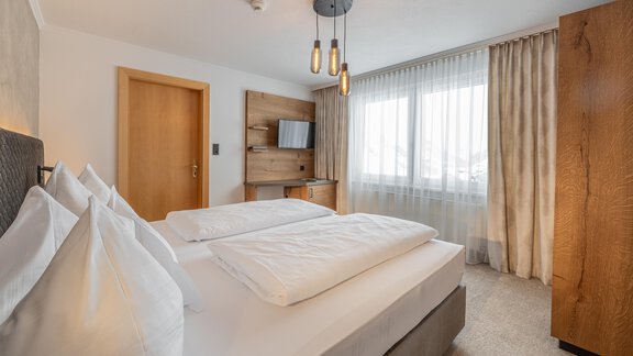 A modern hotel room with two beds and large windows. The decor is bright and inviting, with elegant decoration and soft lighting. - Hotel Olympia - Obergurgl 
