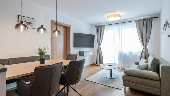 A modern living room with a dining area and a cozy couch. Large windows let in plenty of daylight. - Mein Gaisberg - Obergurgl 