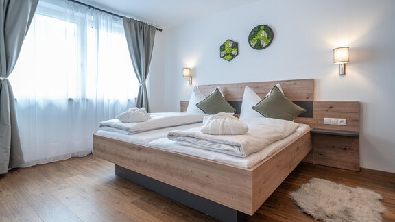 A modern bedroom with a double bed and two pillows. Large windows let in plenty of light and create a bright, inviting atmosphere. - Mein Gaisberg - Obergurgl 