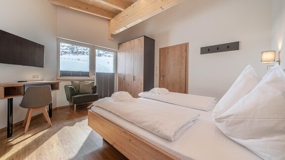 A modern bedroom with wooden furniture and large windows. The atmosphere is bright and inviting. - Mein Gaisberg - Obergurgl 