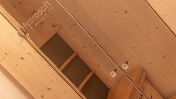 A minimalist room with light wood and a mirror. In the background, shelves and soft lighting are visible. - Mein Gaisberg - Obergurgl 