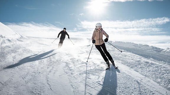 Two skiers are skiing on a snowy slope. The sun is shining clearly in the sky and the snow glitters in the winter landscape. - Mountain Lodge Obergurgl - Obergurgl 