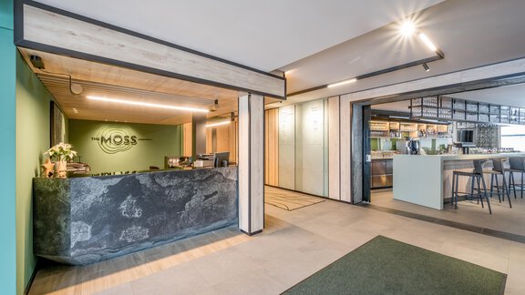 A modern reception area with a stylish reception desk and minimalist decor. The bright colors and elegant design create an inviting atmosphere. - The Moss - Your unique hideaway - Obergurgl 