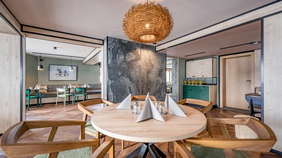A modern restaurant with a round wooden table and comfortable chairs. The decor is elegant and bright with a beautiful pendant light. - The Moss - Your unique hideaway - Obergurgl 