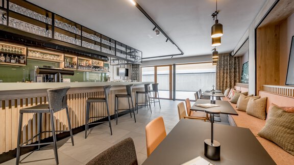 A modern bar with elegant chairs and a well-stocked counter. Large windows provide plenty of natural light and an inviting atmosphere. - The Moss - Your unique hideaway - Obergurgl 