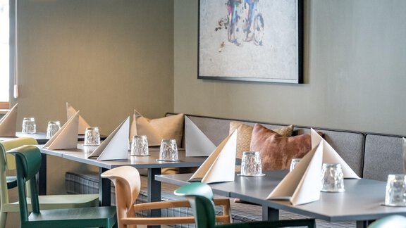 A modern restaurant with wooden chairs and tables. The walls are painted in soft colors and a piece of art hangs on the wall. - The Moss - Your unique hideaway - Obergurgl 