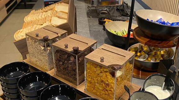 A buffet with various breakfast ingredients, including bread, muesli, and milk. There are also numerous bowls and ladles for the guests. - The Moss - Your unique hideaway - Obergurgl 