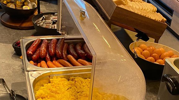 A breakfast buffet with scrambled eggs, sausages, and fresh eggs. In the background, various types of bread and snacks are visible. - The Moss - Your unique hideaway - Obergurgl 