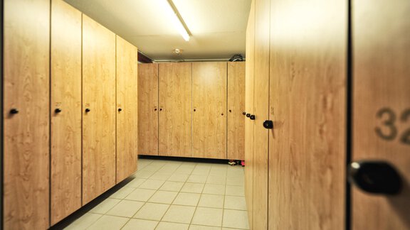 A room with several wooden cabinets and a bright floor. The cabinets are neatly lined up and have numbers. - Haus Timmelseck - Obergurgl 