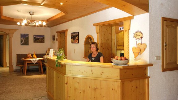A reception area with a wooden counter and a nice employee. The walls are decorated with pictures and the room feels friendly and inviting. - Haus Wendlhof - Obergurgl 