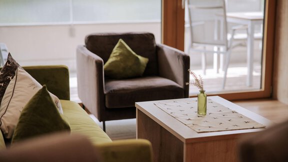 Ein moderner Wohnbereich mit gemütlichen Sesseln und einem Holztisch. Auf dem Tisch steht eine kleine Vase mit einer Pflanze. - Apartment Waldesruh - Ochsengarten
