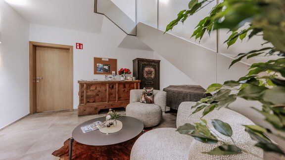 Ein modernes Wohnzimmer mit bequemen Sitzmöbeln und einem runden Tisch. Die helle Umgebung wird durch eine Pflanze und geschmackvolle Dekorationen ergänzt. - Apartment Waldesruh - Ochsengarten