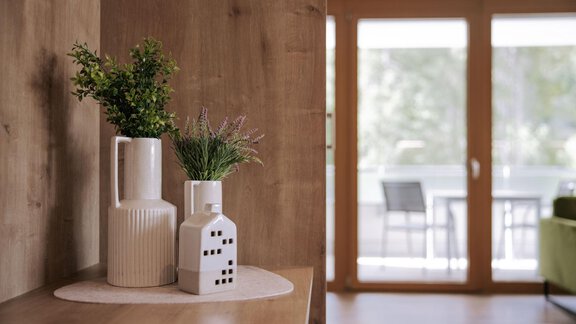 Eine stilvolle Inneneinrichtung mit dekorativen Vasen und Pflanzen. Im Hintergrund sind große Fenster, die natürliches Licht hereinlassen. - Apartment Waldesruh - Ochsengarten