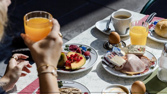 Ein Frühstückstisch mit verschiedenen Speisen wie frischem Obst, Aufschnitt und Brötchen. Dazu werden Kaffee und Orangensaft serviert. - Gasthof Waldesruh - Ochsengarten