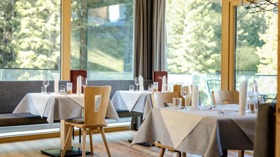 Ein elegantes Restaurant mit hellen Fenstern und einem Blick auf die Natur. Die Tische sind stilvoll mit weißen Tischdecken und Gläsern gedeckt. - Gasthof Waldesruh - Ochsengarten