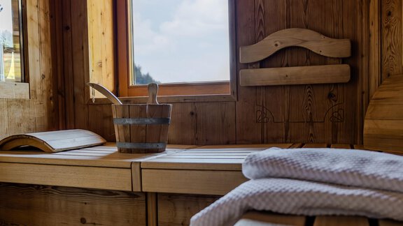 Eine gemütliche Sauna mit Holzinterieur und großen Fenstern. Auf der Bank liegen Handtücher bereit. - Gasthof Waldesruh - Ochsengarten
