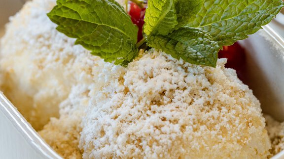 Zwei Kugeln Eis in einer weißen Schale, garniert mit frischer Minze und roter Frucht. Die Oberfläche ist mit einer feinen Schicht Zucker bestreut. - Gasthof Waldesruh - Ochsengarten