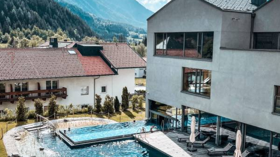 A modern pool area with sun loungers and a view of the mountains. The sun is shining through the clouds, creating a relaxed atmosphere. - All-Suite Resort Ötztal - Oetz