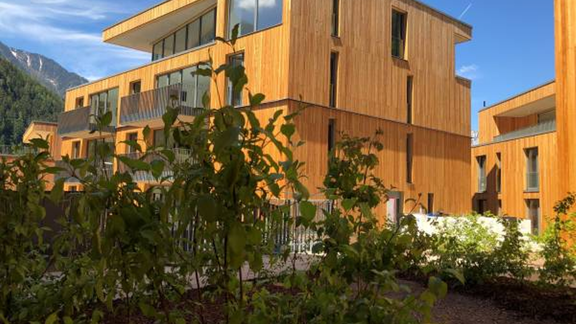 Modern wooden buildings are situated in a green environment. The architecture is clear and harmonizes with nature. - All-Suite Resort Ötztal - Oetz