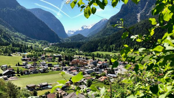 A picturesque mountain landscape with a small village in a green valley. The mountains surround the scene and the sky is clear and blue. - All-Suite Resort Ötztal - Oetz