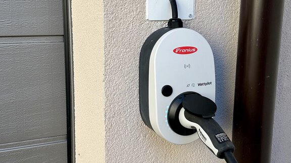Eine Ladestation für Elektroautos ist an der Wand montiert. Der Stecker ist mit der Station verbunden und bereit zum Laden. - ALPsmart - Oetz