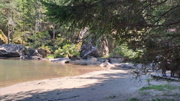 A quiet beach with clear water and surrounding trees. In the background, some rocks and a relaxed atmosphere can be seen. - Apart Annabell - Oetz