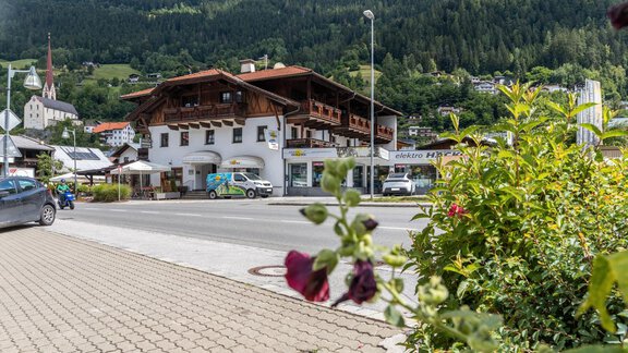 A picturesque village with traditional buildings and green mountains in the background. In the front, roses are blooming. - Apart Celina - Oetz