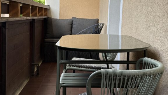 A balcony with a table and two chairs. In the background, there are mountains and trees. - Appartements Schmid Peter - Oetz