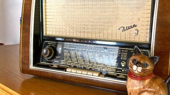A nostalgic radio is on a wooden shelf. Next to it is a decorative ceramic cat. - Haus Evi - Oetz