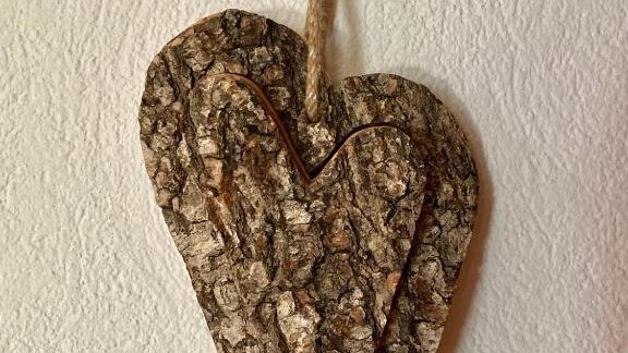 A decorative heart made of bark hangs on a string. It is composed of several overlapping layers in natural earth tones. - Haus Evi - Oetz