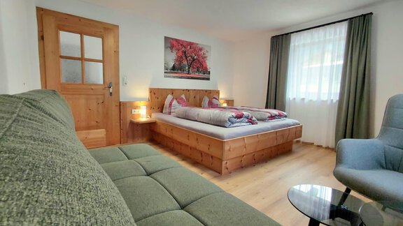 A cozy bedroom with a large bed and a comfortable couch. The room is bright and cheerful with a beautiful piece of artwork on the wall. - Haus Gstrein - Oetz