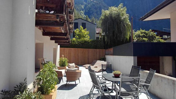 An inviting terrace with seating and a view of an impressive mountain. The sun is shining and there is a relaxed atmosphere. - Haus Gstrein - Oetz