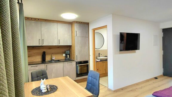 A modern room with a small kitchen and a dining table. The space is bright and well furnished. - Haus Gstrein - Oetz