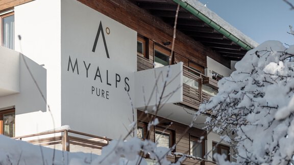 A modern building with the inscription "MYALPS PURE" is surrounded by snow. The architecture combines wood and clean lines in a wintry landscape. - MYALPS Pure - Oetz
