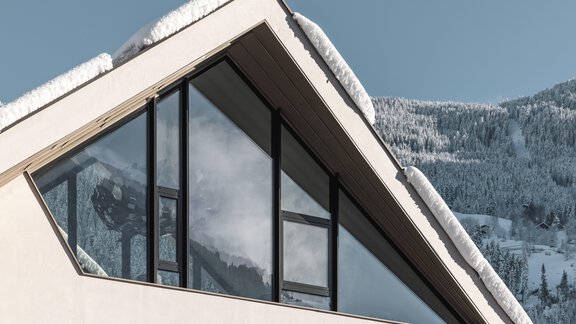 Ein modernes Haus mit einem schrägen Dach und großen Fenstern. Schnee liegt auf dem Dach, und im Hintergrund sind die verschneiten Berge zu sehen. - MYALPS Tirol - Oetz