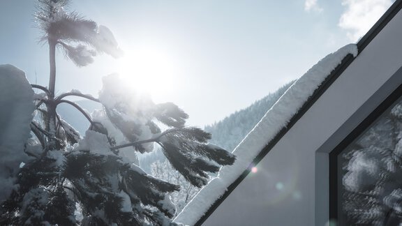 Eine schneebedeckte Landschaft mit einem modernen Gebäude. Die Sonne scheint hell am Himmel und erzeugt eine warme Stimmung. - MYALPS Tirol - Oetz